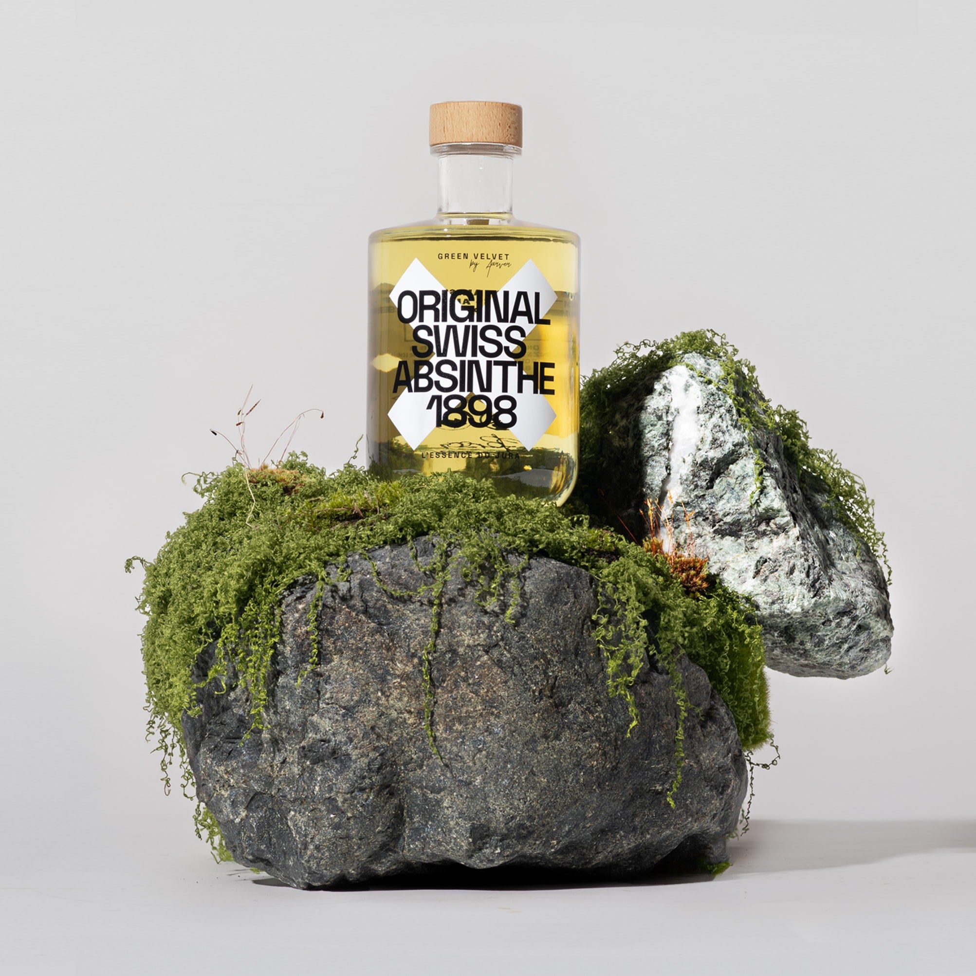 Flasche Green Velvet Original Swiss Absinthe 1898 auf moosbewachsenem Fels mit natürlichem Arrangement aus Steinen und Moos – edle Präsentation eines traditionellen Schweizer Absinths.